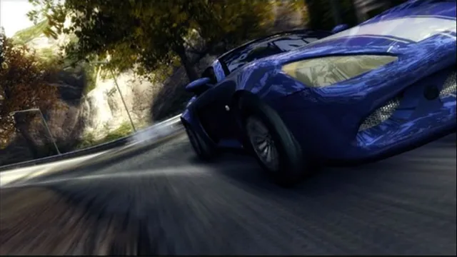 A battered blue sports car speeds around a tree-lined corner in Burnout Revenge.