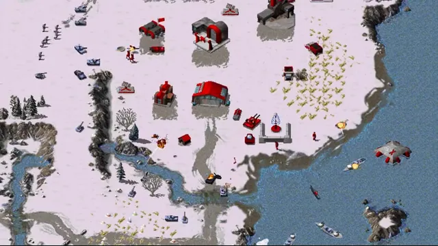 Red tanks, aircraft and base buildings battle beside a snowy coast in OpenRA’s Red Alert ruleset.
